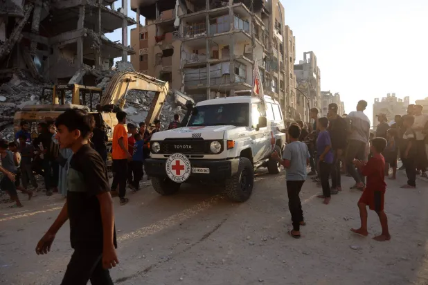 سيارة تتبع الصليب الأحمر تصل إلى موقع يشهد عمليات حفر للبحث عن جثث رهائن إسرائيليين في خان يونس (أ.ف.ب)