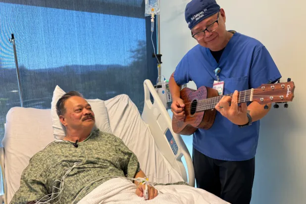Nurse Rod Salaysay plays guitar for patient Richard Hoang in the recovery unit of UC San Diego Health in San Diego, Calif., on Sept. 30, 2025. (AP Photo/Javier Arciga)