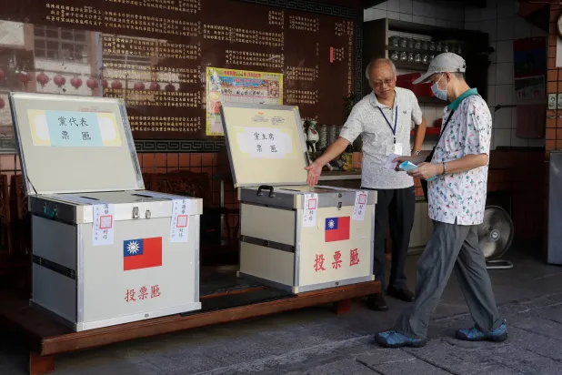 أحد أعضاء حزب «كومينتانغ» يدلي بصوته في تايبيه يوم 18 أكتوبر (أ.ب)