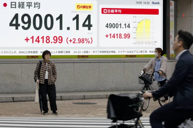 مشاة يمرون أمام لوحة إلكترونية تعرض حركة الأسهم في وسط العاصمة اليابانية طوكيو (إ.ب.أ)