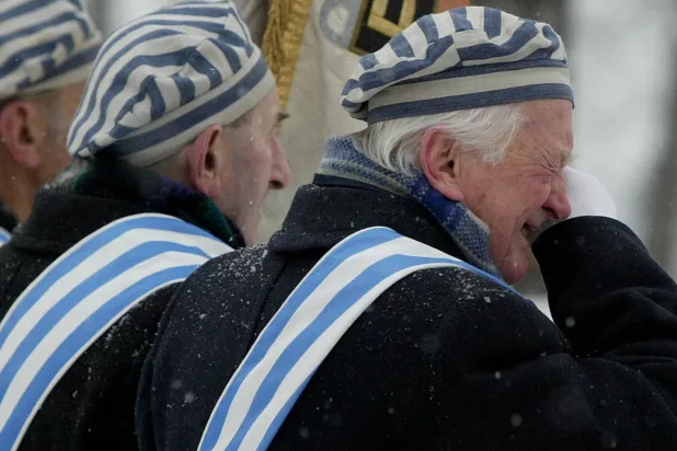 ناجٍ من معسكر اعتقال يمسح دمعة خلال مراسم أقيمت في معسكر الإبادة النازي السابق أوشفيتز بيركيناو ببولندا في 27 يناير 2005 (رويترز)