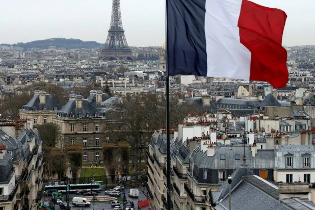 العلم الفرنسي يرفرف فوق أفق باريس مع برج إيفل (رويترز)