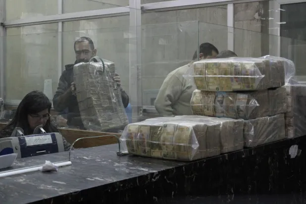 رزم من الأوراق النقدية السورية مكدسة بينما يقوم موظف بعدّ النقود في البنك المركزي السوري (أرشيفية - رويترز)
