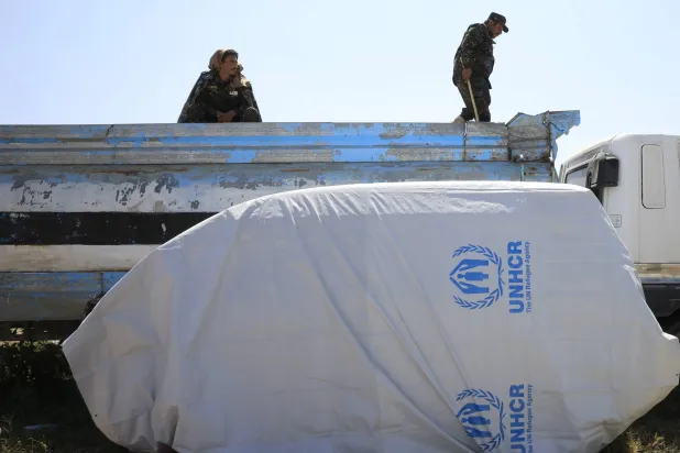 عناصر حوثيون في صنعاء قرب غطاء بلاستيكي يحمل شعار المفوضية السامية للأمم المتحدة لشؤون اللاجئين (إ.ب.أ)