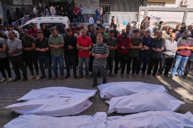 فلسطينيون يصلون على جثامين الشهداء الذين سقطوا بغارة عسكرية إسرائيلية الأحد خلال تشييعهم في مستشفى عودة بالنصيرات وسط قطاع غزة (أ.ب)