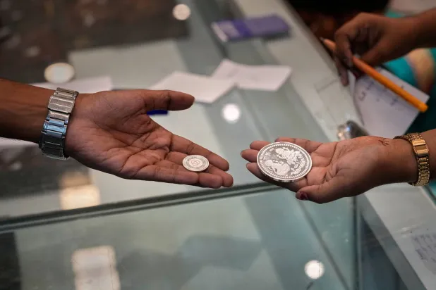 بائعة تُظهر عملة فضية لزبون في يوم دانتيراس وهو يوم ميمون لشراء الذهب والفضة في غواهاتي (أ.ب)