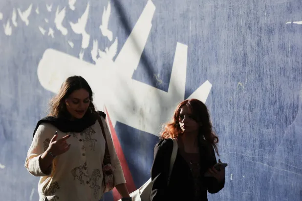 إيرانيتان تمران أمام جدارية مناهضة للولايات المتحدة في أحد شوارع طهران(رويترز)