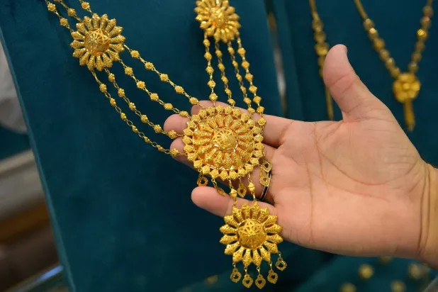 صائغ يبيع الحلي الذهبية بسوق في بيشاور بباكستان (إ.ب.أ)