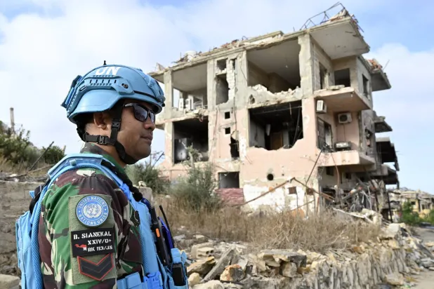 جندي من قوة الأمم المتحدة المؤقتة في لبنان (اليونيفيل) يقف بجانب أنقاض المباني المدمرة في قرية العديسة بجنوب لبنان (إ.ب.أ)