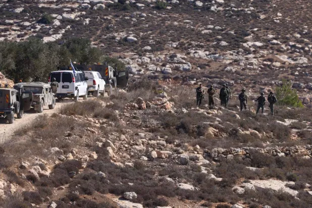 جنود إسرائيليون يتمركزون في قرية على مشارف رام الله بينما يحصد فلسطينيون الزيتون الاثنين الماضي (أ.ف.ب)