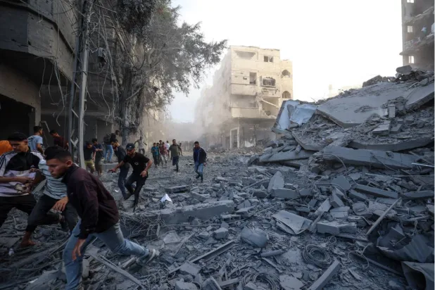 يركض فلسطينيون بحثاً عن ملجأ بعد غارة إسرائيلية استهدفت مبنى في مخيم البريج للاجئين بوسط قطاع غزة (أ.ف.ب)