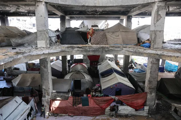 خيام داخل مبنى تهدمت جدرانه جراء العمليات العسكرية الإسرائيلية في حي الزيتون بمدينة غزة (أ.ف.ب)