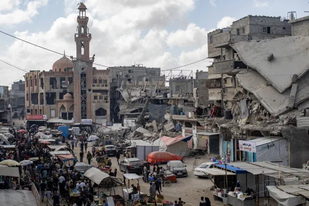 فلسطينيون في سوق محلية بمخيم خان يونس للاجئين جنوب قطاع غزة الجمعة (إ.ب.أ)