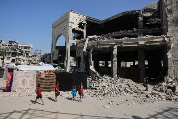 أطفال فلسطينيون نازحون يقفون خارج مسجد متضرر حيث لجأت العائلات في حي الزيتون بمدينة غزة (أ.ف.ب)