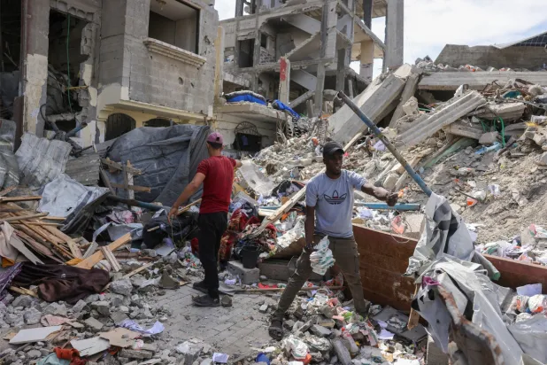 فلسطينيون يتفقدون الأضرار وسط أنقاض مبنى تضرر جراء غارة إسرائيلية في جباليا خلال وقت سابق  (أ ف ب)