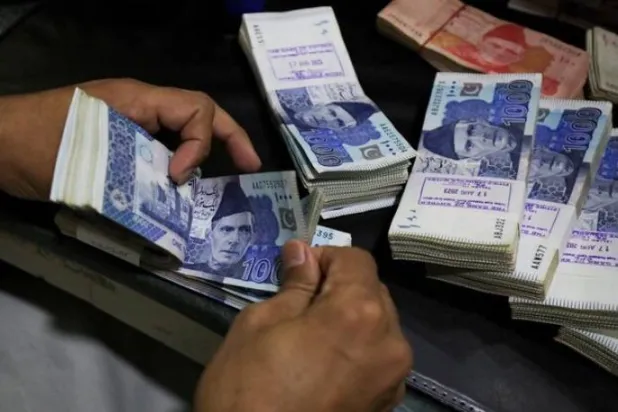 موظف يعد أوراقاً نقدية بالروبية الباكستانية في بنك بمدينة بيشاور (رويترز)