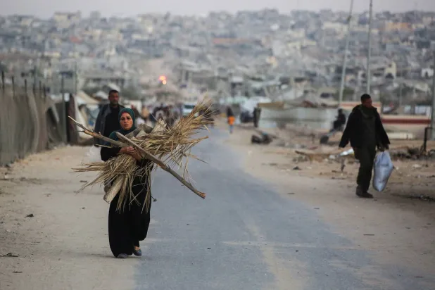 امرأة فلسطينية تحمل حطباً لإشعال النار في خان يونس جنوب قطاع غزة (أ.ف.ب)
