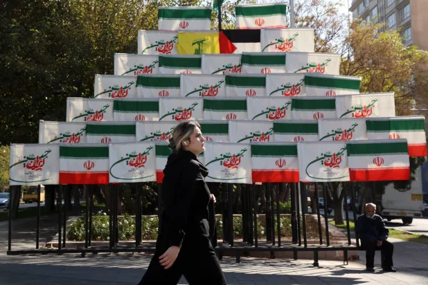 امرأة إيرانية تمر بجانب أعلام معروضة في أحد شوارع طهران الاثنين (إ.ب.أ)