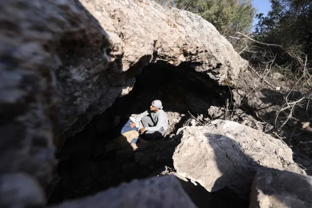 فلسطيني ينظر داخل كهف قُتل فيه 3 فلسطينيين على يد القوات الإسرائيلية قرب مدينة جنين بالضفة الغربية الثلاثاء (أ.ف.ب)