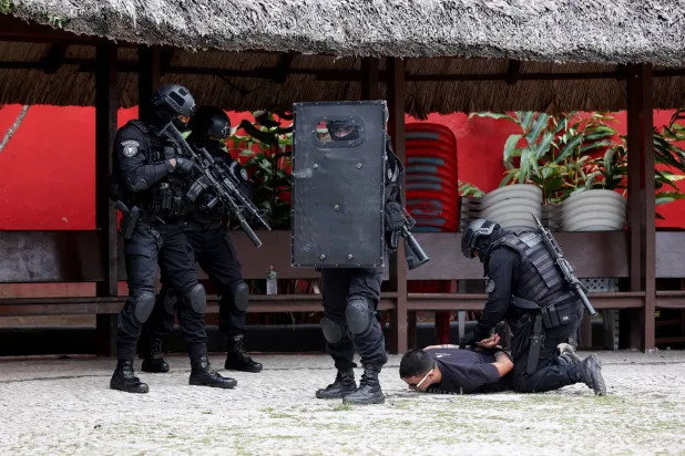 رجل محتجز على الأرض أثناء تدريب أمني أجرته الشرطة العسكرية البرازيلية قبل مؤتمر الأمم المتحدة لتغير المناخ (رويترز) 