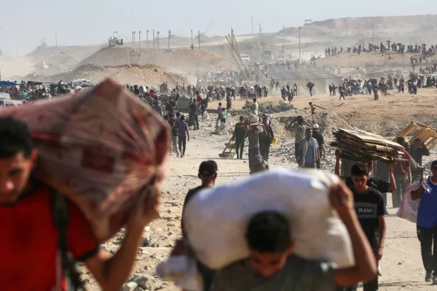 فلسطینیانی که در حال حمل کیسههای کمکهای انسانی در النصیرات، وسط غزه هستند (AFP)