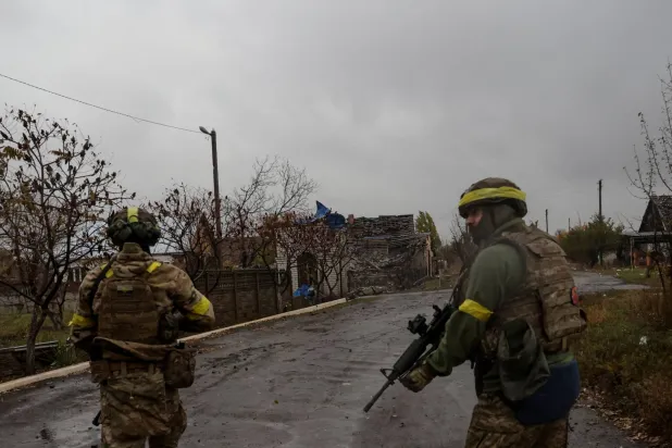 جنود أوكرانيون يسيرون في أحد الشوارع في بلدة ليمان الواقعة على خط المواجهة في منطقة دونيتسك في 27 أكتوبر 2025 (رويترز)