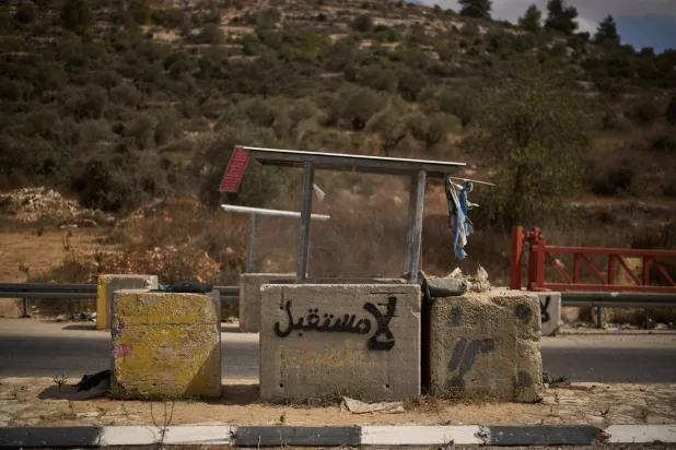 «لا مستقبل» مكتوبة باللغة العربية على كتلة خرسانية يستخدمها جنود إسرائيليون لحراسة وتفتيش السيارات على طريق بالقرب من قرية عين سينيا بالضفة الغربية (أ.ب)