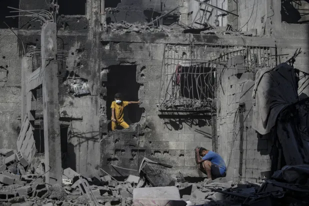 فلسطينيون وسط أنقاض مبان مدمرة بعد هجوم جوي إسرائيلي بمخيم الشاطئ للاجئين في مدينة غزة يوم الأربعاء (إ.ب.أ) 