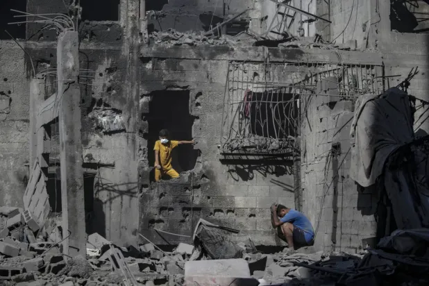 İsrail'in dün Gazze'nin batısındaki eş-Şati Mülteci Kampı’na düzenlediği hava saldırısının ardından yıkılan binaların enkazı arasında duran Filistinliler (EPA)