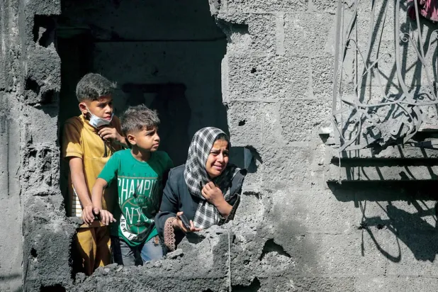 Gazze Şehri'ndeki el-Şati mülteci kampını hedef alan İsrail hava saldırısının ardından yıkılan evlerinden dışarı bakan iki Filistinli çocuk ve anneleri (EPA)