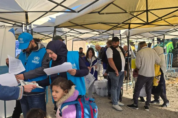 موظفون في الأمم المتحدة ورجال أمن لبنانيون يدققون في أوراق السوريين العائدين (الشرق الأوسط)