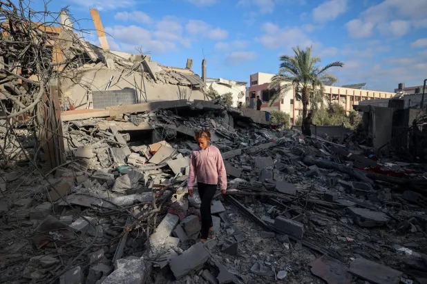 فتاة تمشي وسط أنقاض منزل دمره القصف الإسرائيلي في النصيرات وسط قطاع غزة (أ.ف.ب)