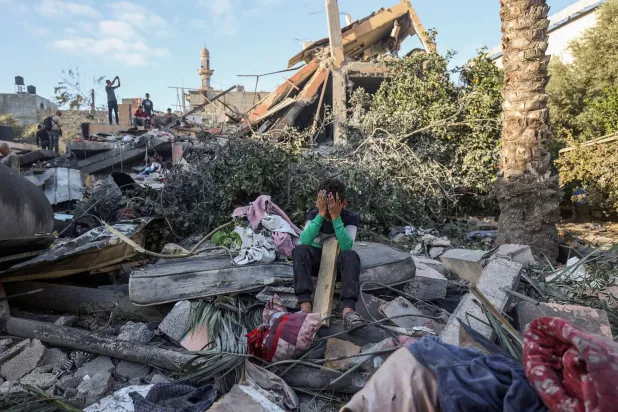 طفل يجلس وسط أنقاض منزل دمره القصف الإسرائيلي في النصيرات وسط قطاع غزة (أ.ف.ب)