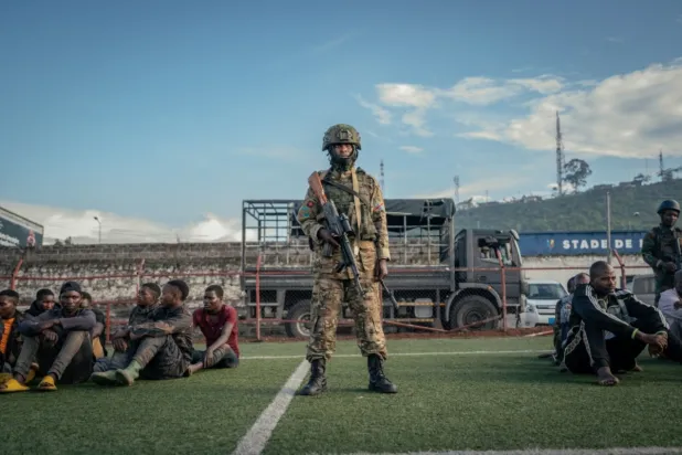 M23 hareketinden bir asker, Ruanda'nın Kurtuluşu için Demokratik Güçler (FDLR) üyesi yaklaşık 100 kişinin başında nöbet tutarken (AFP)