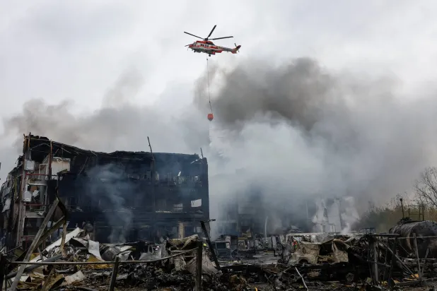 هليكوبتر تسقط المياه على مستودعات الأغذية التي تعرضت لقصف صاروخي روسي في كييف (رويترز)