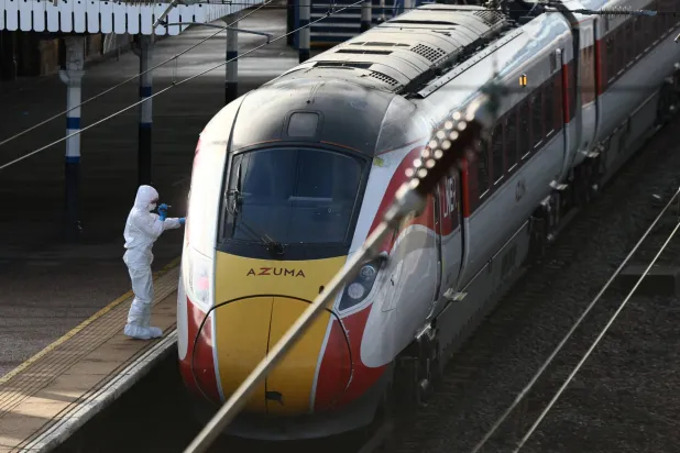 محققو الطب الشرعي يسيرون أمام المنطقة التي ترك فيها المسافرون أمتعتهم بعد طعن جماعي في قطار متجه إلى لندن في هانتينغدون بإنجلترا (رويترز)