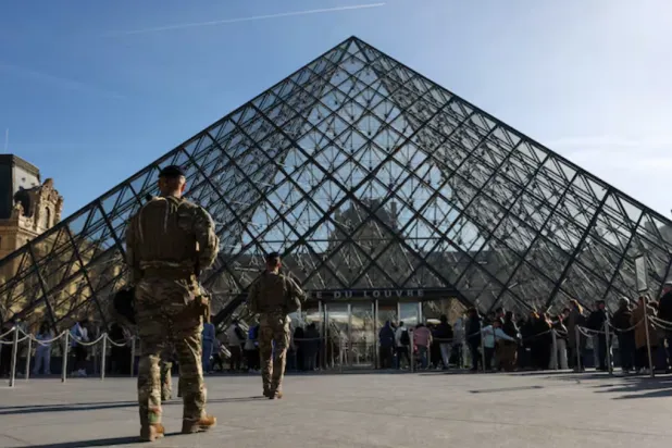 French soldiers from the "Sentinelle" security plan patrol past the glass Pyramid while people queue to enter the Louvre Museum as French police have arrested more suspects linked to the theft of treasures from the Louvre museum's Galerie d'Apollon (Apollo gallery), in Paris, France, October 30, 2025. REUTERS/Abdul Saboor 