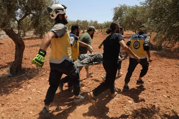 فرق إنقاذ تخلي الضحايا عبر بستان زيتون عقب انفجار هز إدلب في شمال غربي سوريا يوم 14 أغسطس 2025 (أ.ف.ب)