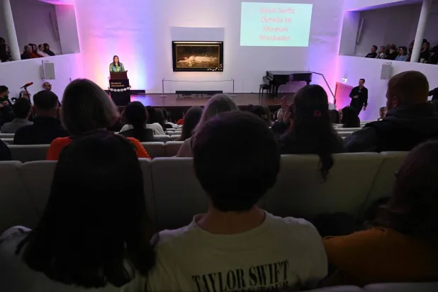 Fans of US singer-songwriter Taylor Swift and other visitors listen to a lecture about the painting 'Ophelia' (ca 1900) by German artist Friedrich Heyser during a short guided tour at the Museum in Wiesbaden, western Germany on November 2, 2025. (Photo by Kirill KUDRYAVTSEV / AFP) 
