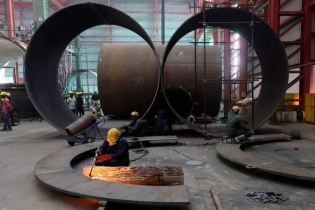 عامل يقطع صفيحة معدنية داخل مصنع لتصنيع الخزانات الصناعية في ضواحي مدينة أحمد آباد (رويترز)