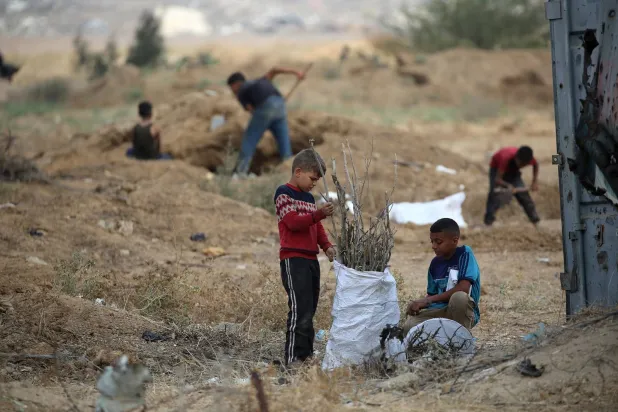 أطفال فلسطينيون يجمعون الحطب لاستخدامه في الطهي وسط نقص الوقود بقرية جحر الديك شرق مخيم البريج وسط غزة يوم الاثنين (أ.ف.ب)