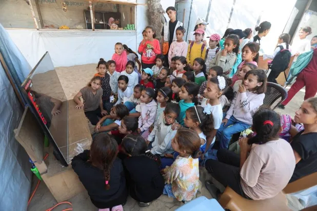  Palestinian children watch a cartoon movie during an activity held by the Palestinian Red Crescent Society, aimed at easing the psychological stress caused by the war, in Khan Younis in the southern Gaza Strip, October 28, 2025. (Reuters)
