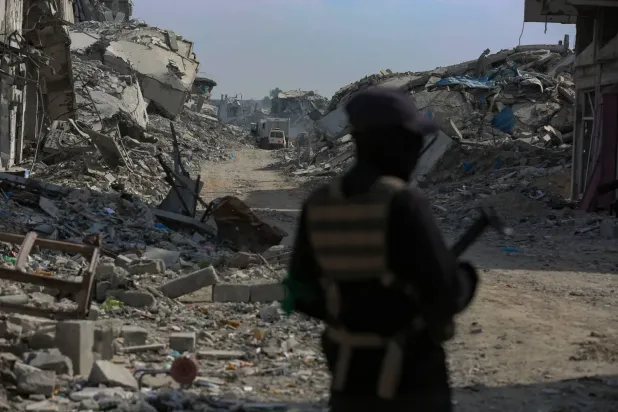 Pazar günü Gazze Şeridi'nin doğusunda İsrailli rehinelerin cesetlerini arama çalışmaları devam ederken görülen Hamas'ın askeri kanadı İzzettin el-Kassam Tugayları üyesi (EPA)