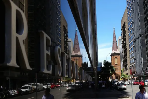 مشاة يمرون بجانب مبنى بنك الاحتياطي الأسترالي في وسط سيدني (رويترز)