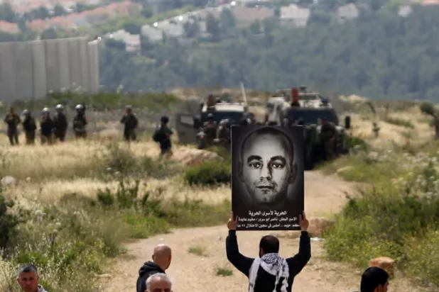 متظاهر فلسطيني يرفع لافتةً عام 2015 تحمل صورة ناصر أبو سرور مطالباً بالإفراج عنه (أ.ف.ب)
