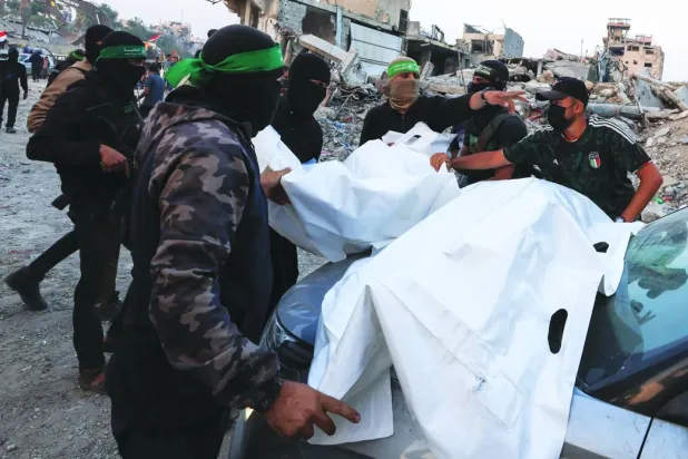 Hamas dün Gazze'de bir İsrail askerinin cesedini bulduğunu ve onu İsrail'e teslim etmeye hazır olduğunu duyurmasının ardından silahlı kişiler cesetleri taşıyor (Reuters)