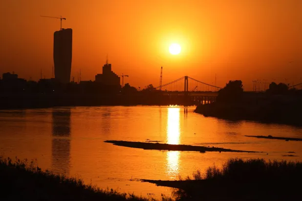 The sun sets over the under-construction Central Bank of Iraq building (L) and the 14th of July Bridge along the banks of the Tigris River in central Baghdad on October 27, 2025. (AFP)