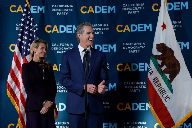 حاكم كاليفورنيا غافين نيوسوم (يمين) يتحدث بينما زوجته جينيفر سيبل نيوسوم (يسار) تُتابعه خلال اجتماع ليلة الانتخابات بمقر الحزب الديمقراطي بكاليفورنيا (أ.ف.ب)