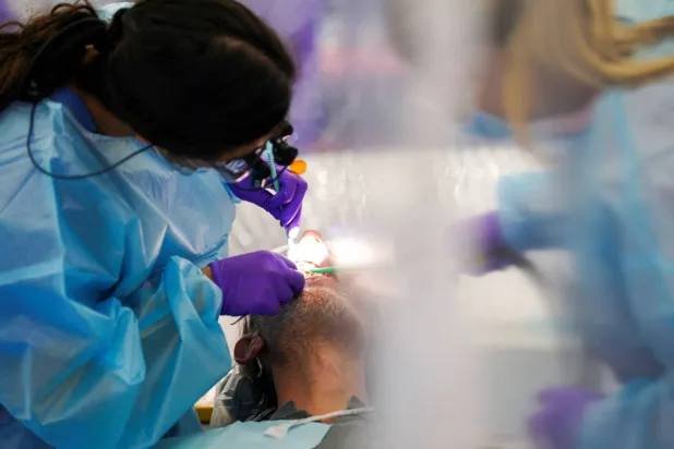 طبيبة أسنان تفحص مريضاً داخل عيادة صحية متنقلة في تينيسي بالولايات المتحدة (رويترز)