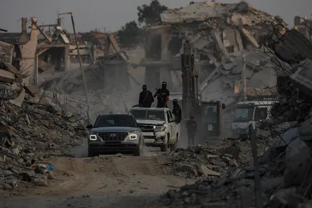 عناصر «كتائب القسام» يبحثون عن جثث رهائن إسرائيليين إلى جانب عمال الصليب الأحمر في حي الشجاعية شرق مدينة غزة (إ.ب.أ)